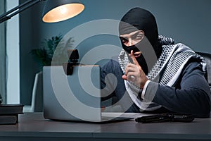 The hacker wearing balaclava mask hacking computer