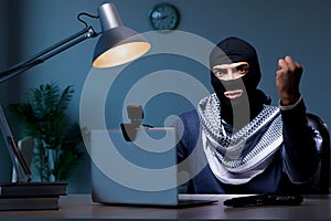 The hacker wearing balaclava mask hacking computer