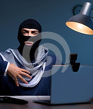 Hacker wearing balaclava mask hacking computer