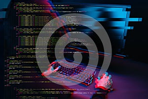 Hacker working with computer in dark room with digital interface around. Image with glitch effect.