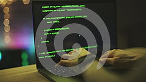 Hacker is working on laptop at night. Hands are typing a virus code at keyboard or hacking website. Closeup. Concept of