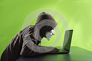 Hacker works with laptop and wearing vendetta mask