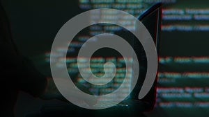 Hacker writing code cracking computer. Programming code in the background. Hacker attack, cybercrime, virus software, dark web,