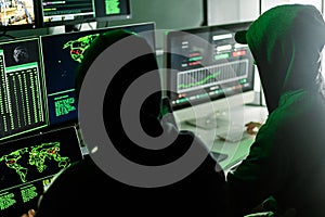 Hackers working on computers showing world maps and security camera footage