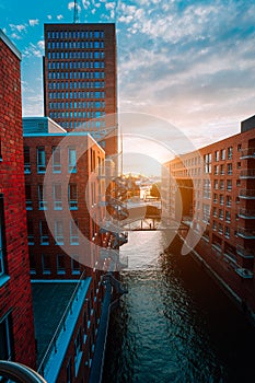 HafenCity. Bridge over canal and red brick buildings in the old warehouse district Speicherstadt in Hamburg in golden