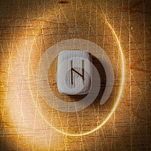 Hagalaz. Handmade scandinavian wooden runes on a wooden vintage background in a circle of light. Concept of fortune