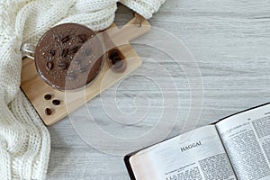 Haggai open holy bible book with coffee cup and cosy woolen scarf, top view