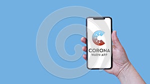 Female Hand Holding Smartphone with Corona-Warn-App developed by Deutsche Telekom and SAP
