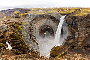 Haifoss waterfall in Fossardalur valley in Iceland, landscape view with a female traveler
