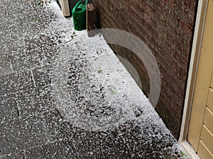 Hail lies on pavement near a house