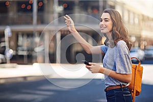 Hailing a cab. an attractive young woman sending a text message while hailing a taxi out in the city.