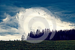 Hailstorm brewing over spring meadow and forest in German countryside photo