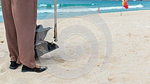 Hainan Island, Sanya, China - May 16, 2019: A cleaning lady picks up trash on Hainan Beach with special handy forceps