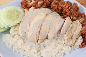 Hainanese chicken rice with Roasted Chicken on wooden table.Hainanese chicken rice is a dish of poached chicken and seasoned rice