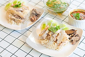 Hainanese Chicken Rice in white plate on the table with soup and spicy dipping sauce