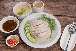 Hainanese chicken rice on a white table background, Steamed chicken rice with spicy sauces and chicken soup,