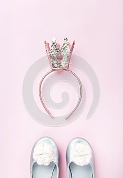 Hair band with a crown and girl's shoes, flatlay on pink