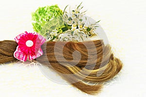 Hair and barrette with pink ribbon, flowers and green leaf on white lace background