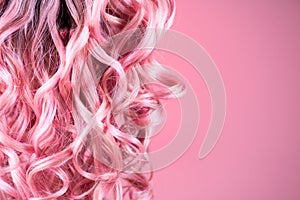 Hair. Beautiful healthy long curly dyed pink color hair close-up texture. Fashion trendy Dyed wavy hair background, coloring