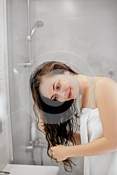Hair and body care. Girl uses protection moisturizing cream and oil. Beautiful young woman touching her wet hair