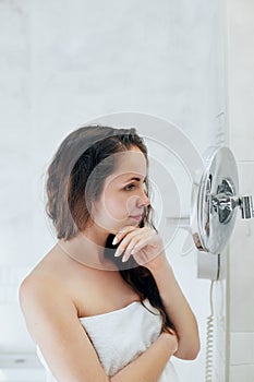 Hair and body care. Woman touching wet hair and smiling while looking in the mirror. Portrait of girl  in bathroom applying condit