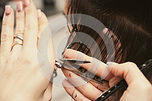 Hair care, beauty industry concept. Hairdresser doing haircut closeup of work. Hairstylist does cutting hair tips of a