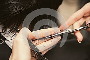 Hair care, beauty industry concept. Hairdresser doing haircut closeup of work. Hairstylist does cutting hair tips of a