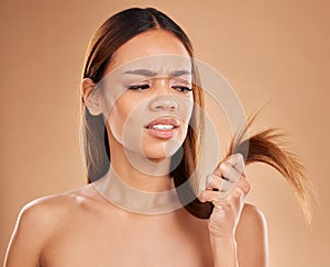 Hair care, frustrated and a woman looking at split ends isolated on a studio background. Unhappy, frizzy and a girl with