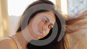 Hair care. Portrait of a young caucasian woman drying her dark hair with a hair dryer. Side view
