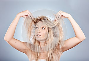 Hair care, stress and woman sad about frizz, split ends and messy style against a grey studio background. Frustrated