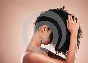 Hair care, touching and a woman styling curls isolated on a brown background in a studio. Salon, cosmetic and model