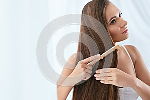 Hair Care. Woman Combing Beautiful Long Hair With Wooden Brush