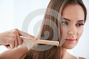 Hair Care. Woman Combing Beautiful Long Hair With Wooden Brush