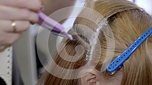 Hair coloring. Close-up of a stylist\'s hands using a professional comb and coloring the roots of a client\'s hair.