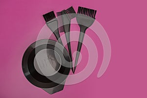 Hair coloring kit, brushes and a bowl on a pink background, beauty tools, copy space