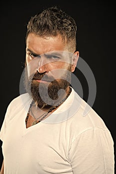 Hair design trends. Serious hipster with long beard and stylish hair on black background. Bearded man with unshaven face