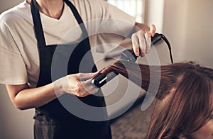 Hair doesnt make the woman, but good hair definitely helps. a hairstylist using a curling iron to do her clients hair.