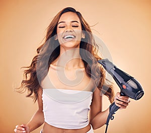 Hair dryer, happy and a woman in studio for beauty, cosmetics and shine. Aesthetic model person laugh on brown