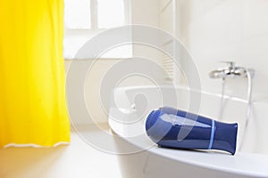 Hair dryer lying on a bathtub in a bright bathroom danger of electric shock