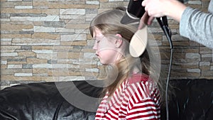 Hair drying process. Mom dries hair with hairdryer of cute beautiful blonde daughter. Hair care.