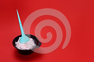 hair dye with a brush in a bowl on a red background. Space for text