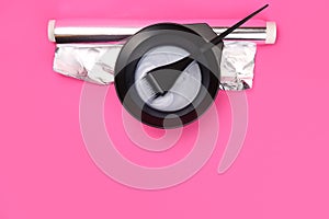 hair dye with brush in mixing bowl on pink background. Copy space