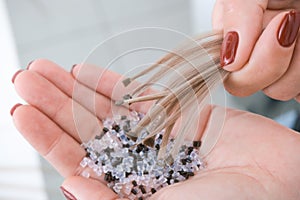 Hair extension. Hair strands with capsules in hand photo