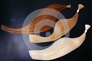 Hair extensions of three colors on a dark background. copyspace. top view.