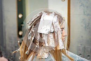 Hair foiled during hair dyeing of a young woman in hair salon close up.