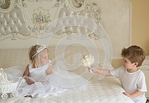 Hair and inspiration. Page boy with blond hair hold wedding bunch. Little flower girl wear tiara crown and hairstyle