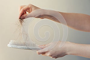 Hair loss. Female hand pulls out a clump of hair from a comb. Close-up. The concept of alopecia and trichology