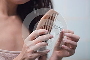 Hair loss and hair care. Hands holding a comb and hair. The girl is combing her hair in the bathroom and a lot of hair fell out