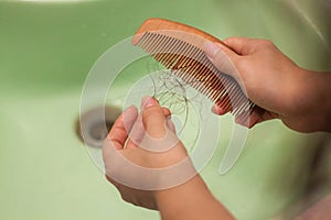 Hair loss and hair care. Hands holding a comb and hair. The girl is combing her hair in the bathroom and a lot of hair fell out