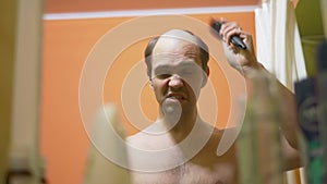 Hair loss problem. balding man looks in the mirror, combes the remaining hair